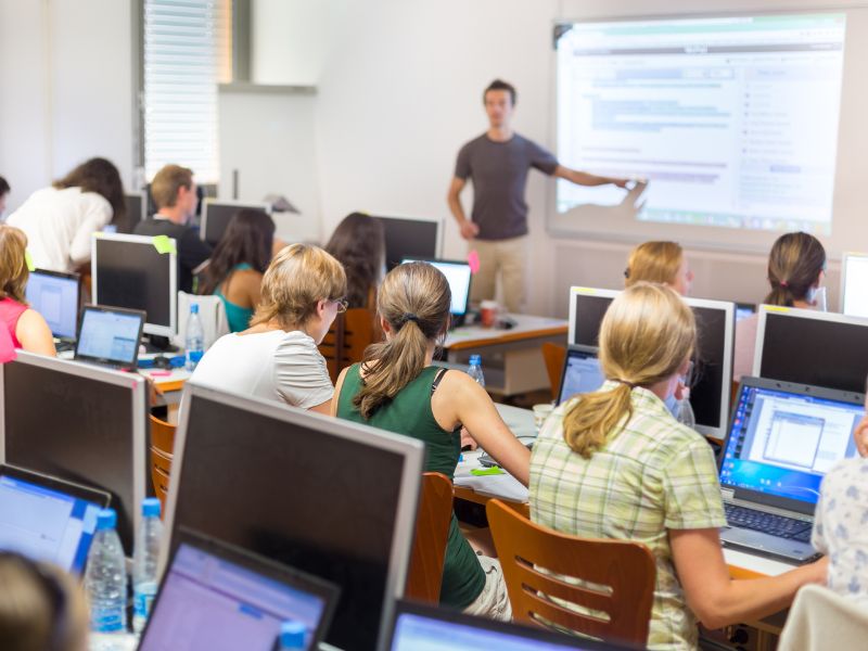 public speaker teaches computer education to a full classroom